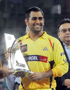 a man holding a trophy while standing next to another man in yellow shirt and tie