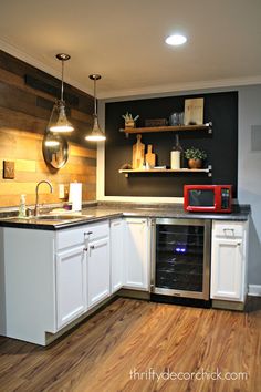 an empty kitchen with white cabinets and wood flooring is pictured in this image, there are lights hanging above the sink