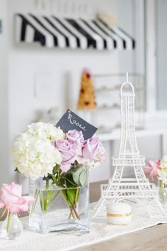 a table topped with vases filled with flowers next to the eiffel tower