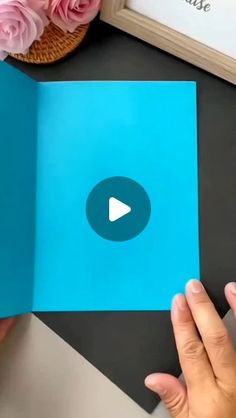 someone is holding an open book with a video playing on the page in front of them