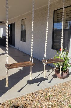 two wooden swings hanging from the side of a building next to a potted plant