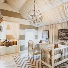 a baby's room with two cribs and a chandelier hanging from the ceiling