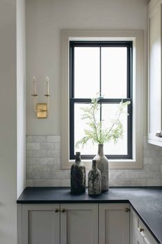 two vases sitting on top of a counter next to a window