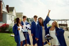 some people in graduation gowns are standing on the street and one person is holding his arms up