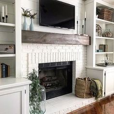 a living room with white brick fireplace and shelves