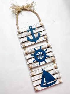 a wooden sign with an anchor, boat and steering wheel on the front hanging from a rope