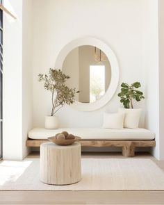 a living room with a white couch and round mirror on the wall, next to a plant