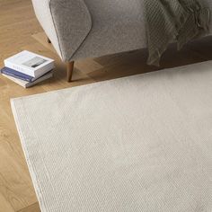 a white rug sitting on top of a wooden floor next to a gray couch and chair