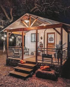 a small cabin is lit up at night with pumpkins on the porch and stairs