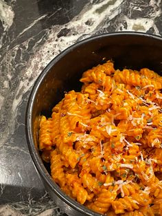 a bowl filled with macaroni and cheese on top of a marble countertop