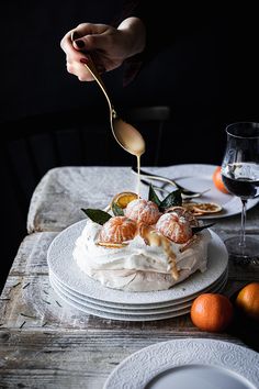 a person is sprinkling icing onto a cake with oranges on the side