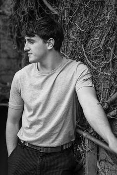 a man leaning against a wall covered in vines