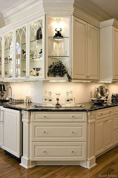 an elegant kitchen with white cabinets and black counter tops is lit by recessed lights