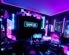 a man sitting in front of a computer monitor on top of a desk covered in neon lights