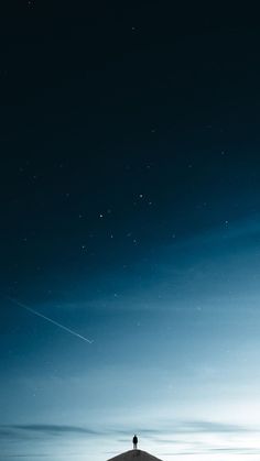 a person standing on top of a snow covered hill under a blue sky with stars