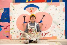 a man sitting on the ground in front of a painting