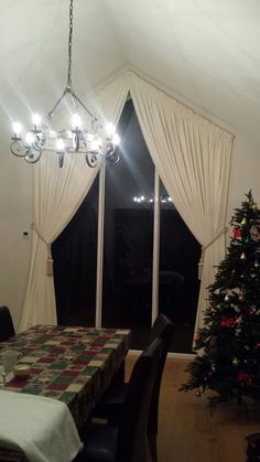 a dining room with a christmas tree in the corner and a chandelier hanging from the ceiling