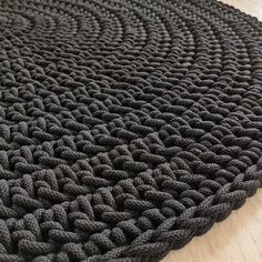 a black knitted rug sitting on top of a wooden floor