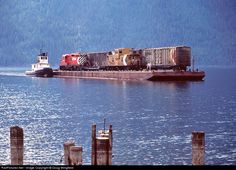 a large cargo ship traveling across a body of water next to a forest covered hillside