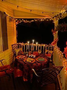 an outdoor dining area is lit up with candles and decorated pumpkins on the table