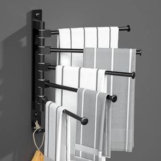 several towels are hanging on a towel rack with black handles and bars, along with a wooden bag