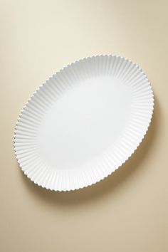 a white paper plate with scalloped edges on a beige surface, viewed from above