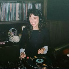 a woman sitting in front of a dj's turntable with headphones on