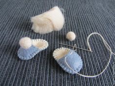 two pieces of felt are sitting on the floor next to some knitting needles and yarn balls