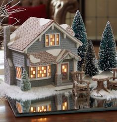 a christmas scene with a lit up house and trees in the snow on a tabletop