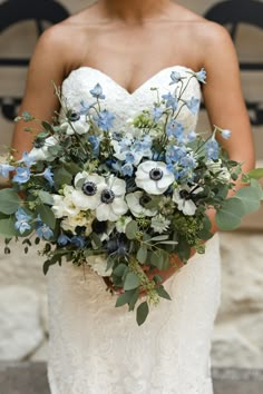 a bride holding a bouquet of blue and white flowers