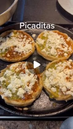 four small pizzas sitting on top of a pan covered in cheese and toppings