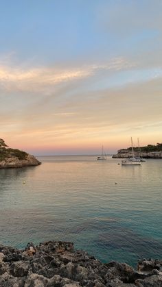 boats are in the water at sunset near an island