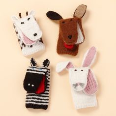 four knitted animals are sitting next to each other on a beige surface, one is wearing a black and white striped sweater