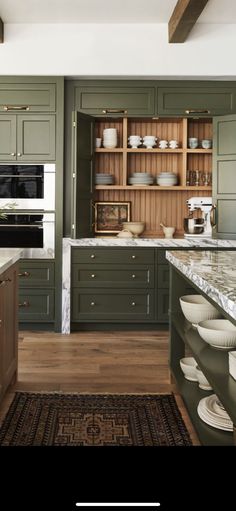 a kitchen with green cabinets and white plates on the counter top, along with an area rug