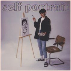 a woman standing in front of an easel with a drawing on it and holding a cell phone