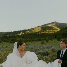 the bride and groom are walking through the field