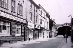 an old black and white photo of a city street with stores on the side of it