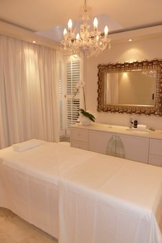 a large white bed sitting in a bedroom under a chandelier