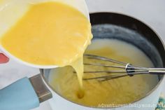 a person pouring batter into a pot filled with yellow liquid and whisked with cream