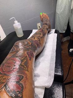 a man with tattoos on his leg sitting in a chair next to a white towel