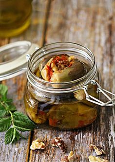 a jar filled with pickles sitting on top of a wooden table next to a spoon