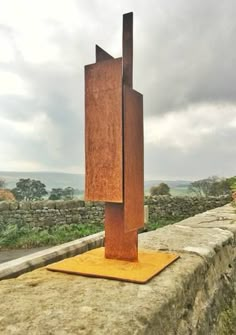 a metal sculpture sitting on top of a stone wall