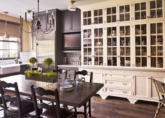 a dining room table and chairs in front of a large china cabinet with glass doors