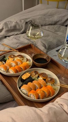 two plates of sushi and wine on a tray