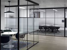 an office with glass walls and tables in the center, along with chairs on either side