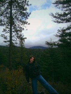 a woman standing on top of a tree covered hillside