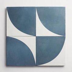 two blue and white square tiles on the wall, one with an abstract design in it