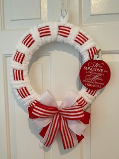 a red and white wreath hanging on the front door with a heart saying someone special