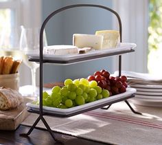 a tray with grapes, cheese and crackers on it sitting on a dining room table