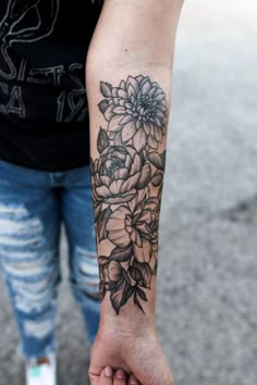 a person with a flower tattoo on their arm holding the hand of another person's wrist